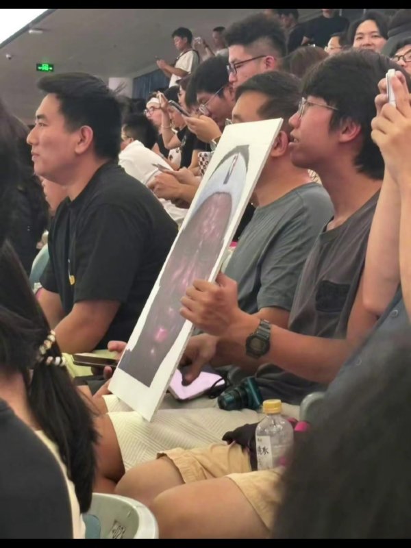詹姆斯中国行成都活动现场 一球迷拿着詹姆斯经典哭脸照坐在场边